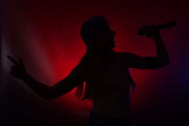 Silhouette of woman singing on dark background with color lights