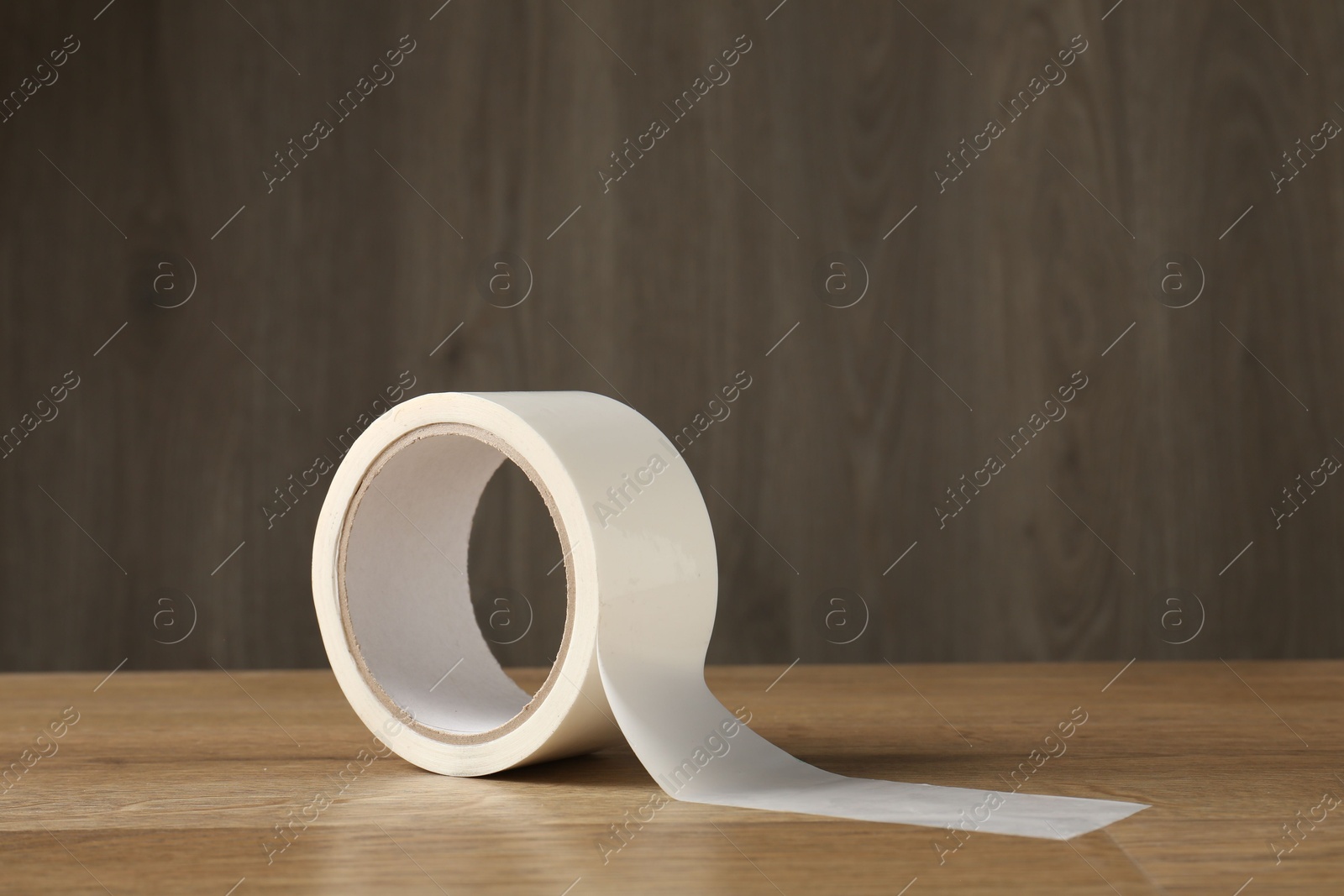 Photo of Roll of masking tape on wooden table, space for text