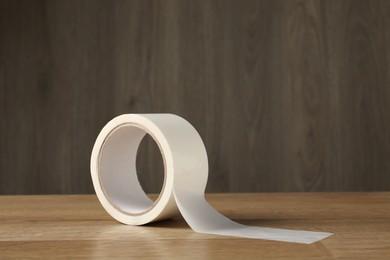 Photo of Roll of masking tape on wooden table, space for text