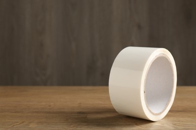 Photo of Roll of masking tape on wooden table, closeup. Space for text