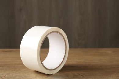 Photo of Roll of masking tape on wooden table, closeup. Space for text