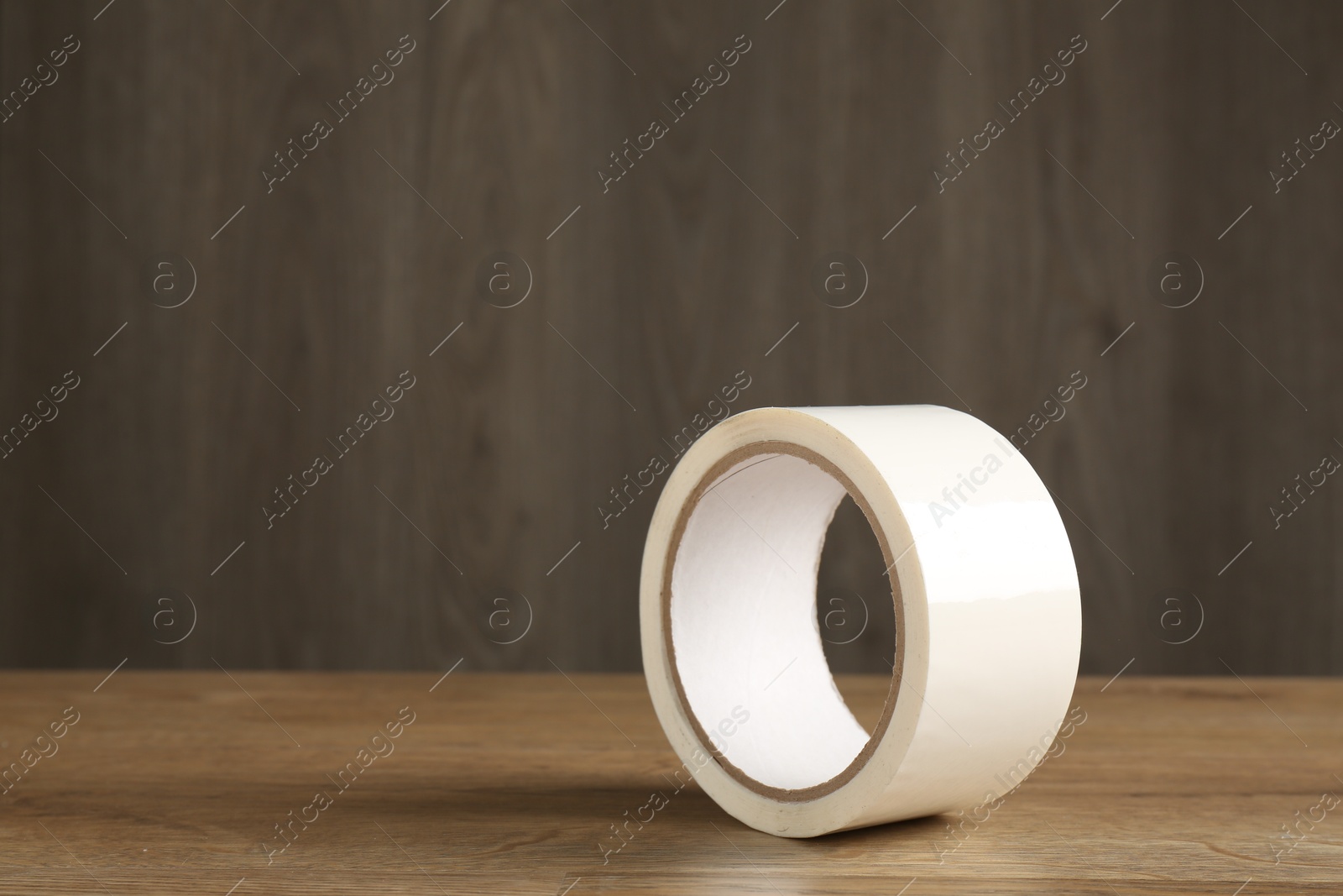 Photo of Roll of masking tape on wooden table, space for text