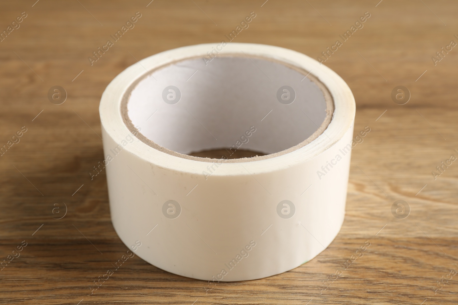 Photo of Roll of masking tape on wooden table, closeup