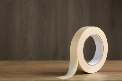 Photo of Roll of masking tape on wooden table, space for text