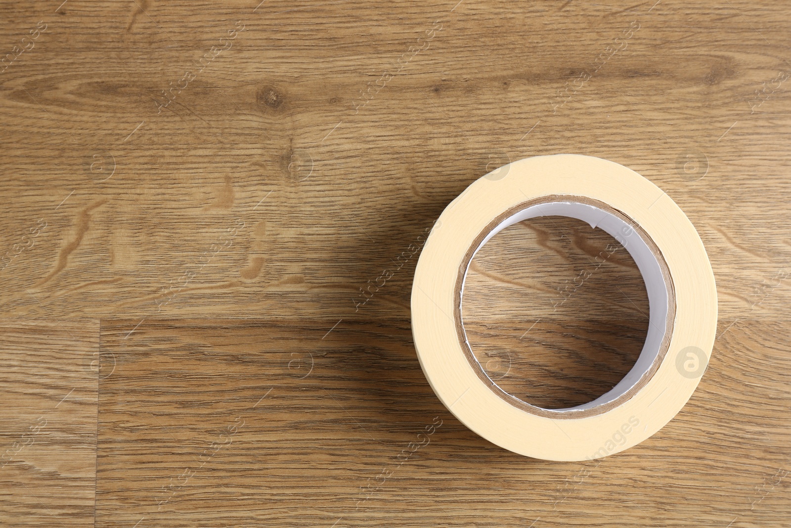 Photo of Roll of masking tape on wooden table, top view. Space for text