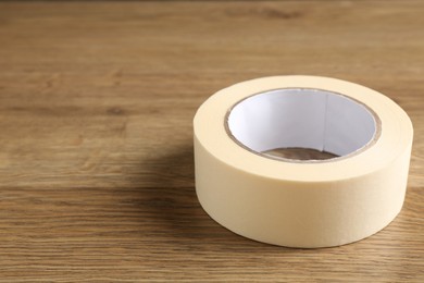 Photo of Roll of masking tape on wooden table, closeup. Space for text