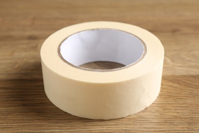 Photo of Roll of masking tape on wooden table, closeup