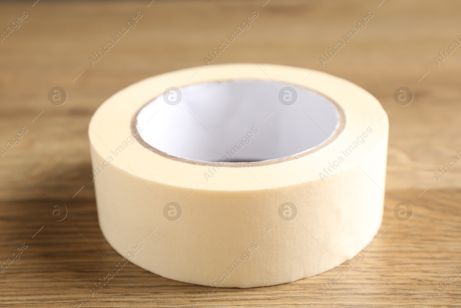 Photo of Roll of masking tape on wooden table, closeup