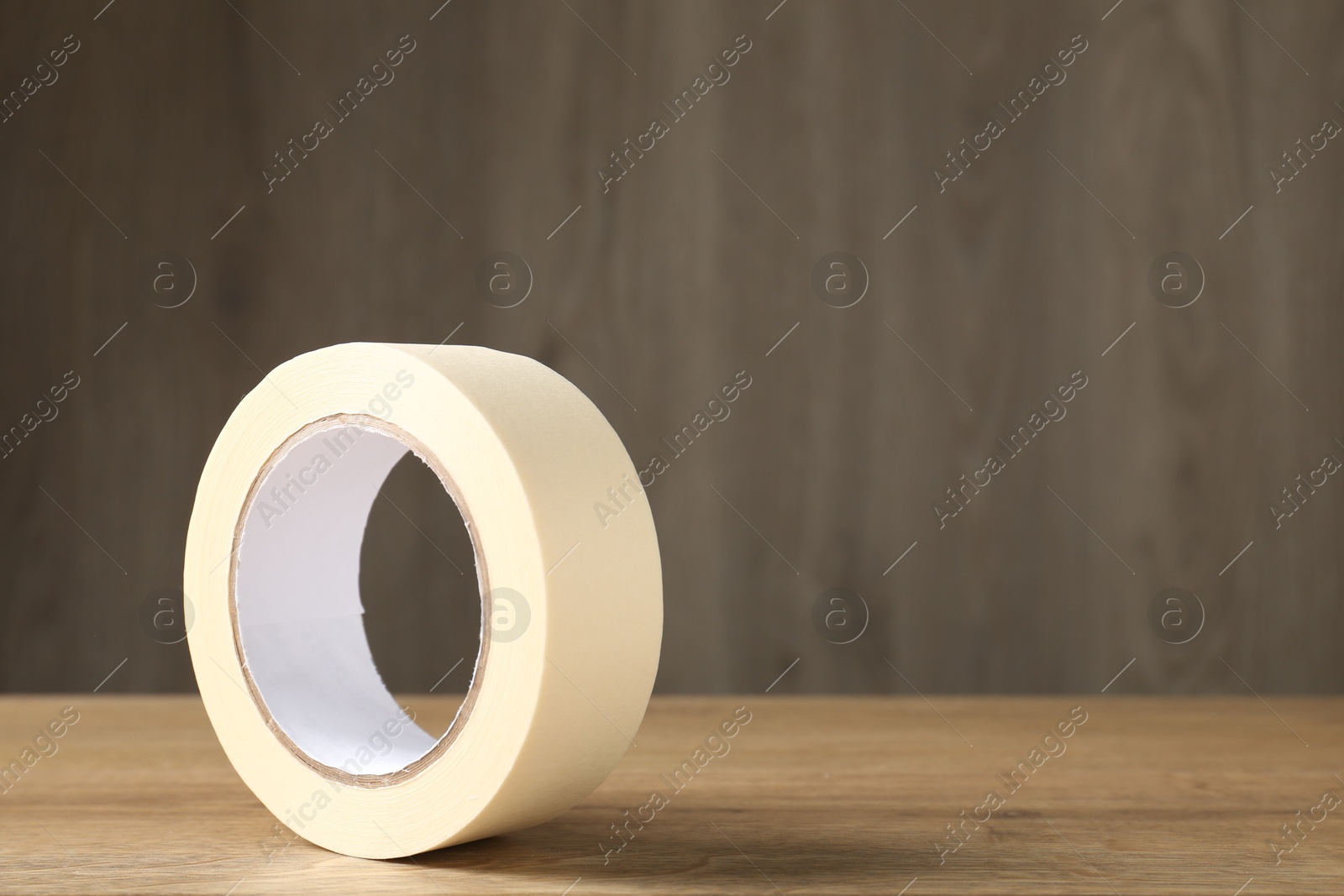 Photo of Roll of masking tape on wooden table, space for text