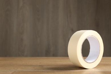 Photo of Roll of masking tape on wooden table, space for text