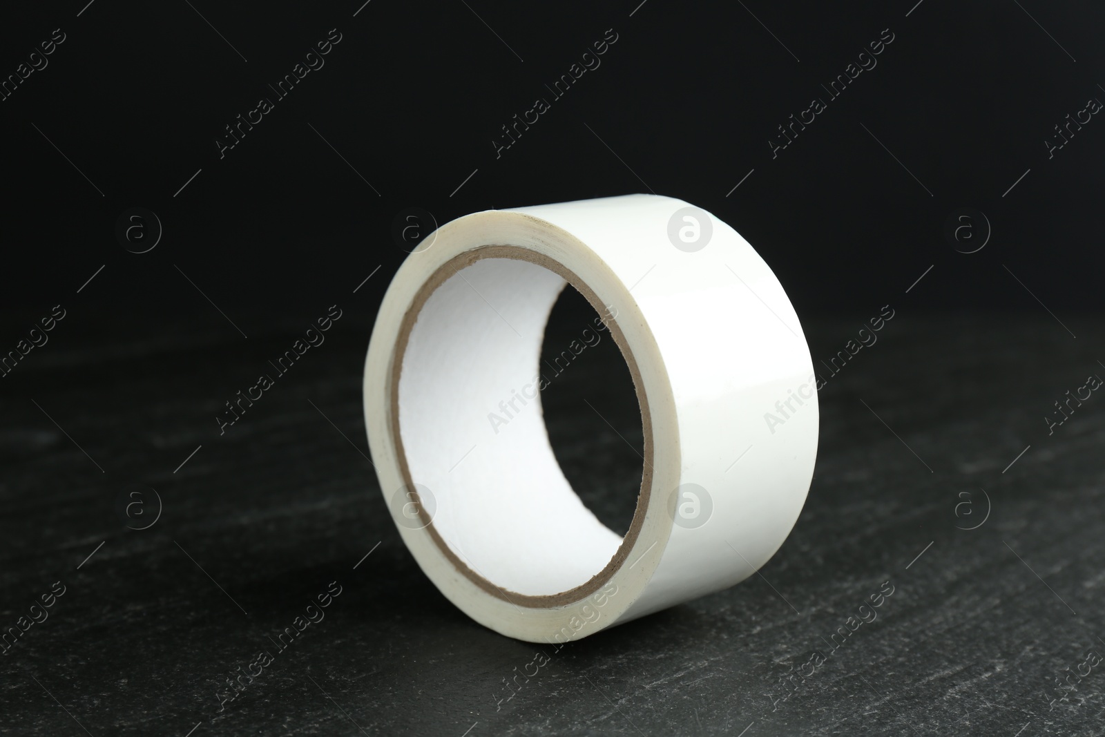 Photo of Roll of masking tape on black table, closeup