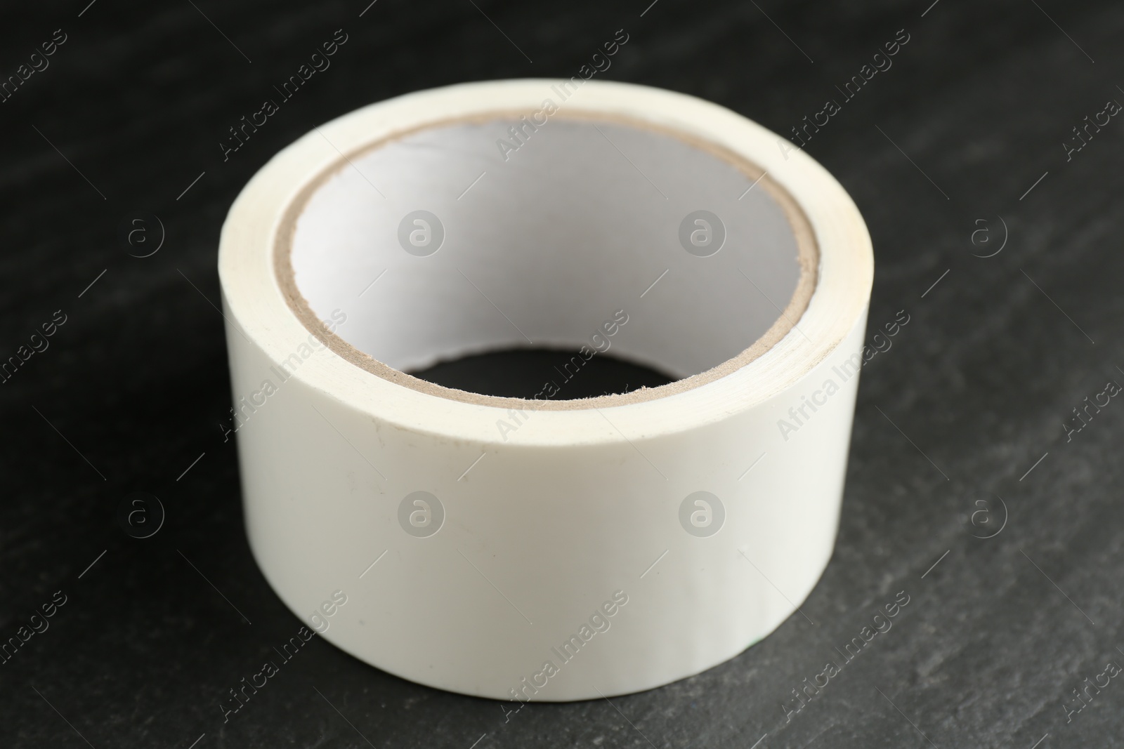 Photo of Roll of masking tape on black table, closeup