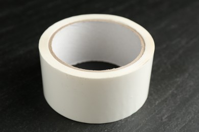 Roll of masking tape on black table, closeup