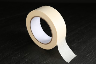 Photo of Roll of masking tape on black table, closeup