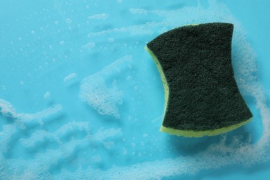 Photo of One cleaning sponge and foam on light blue background, top view. Space for text