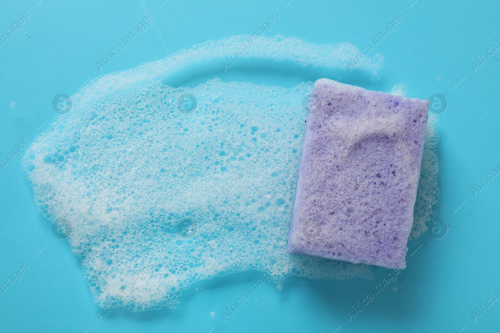 Photo of One cleaning sponge and foam on light blue background, top view. Space for text