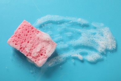 Photo of One cleaning sponge and foam on light blue background, top view. Space for text