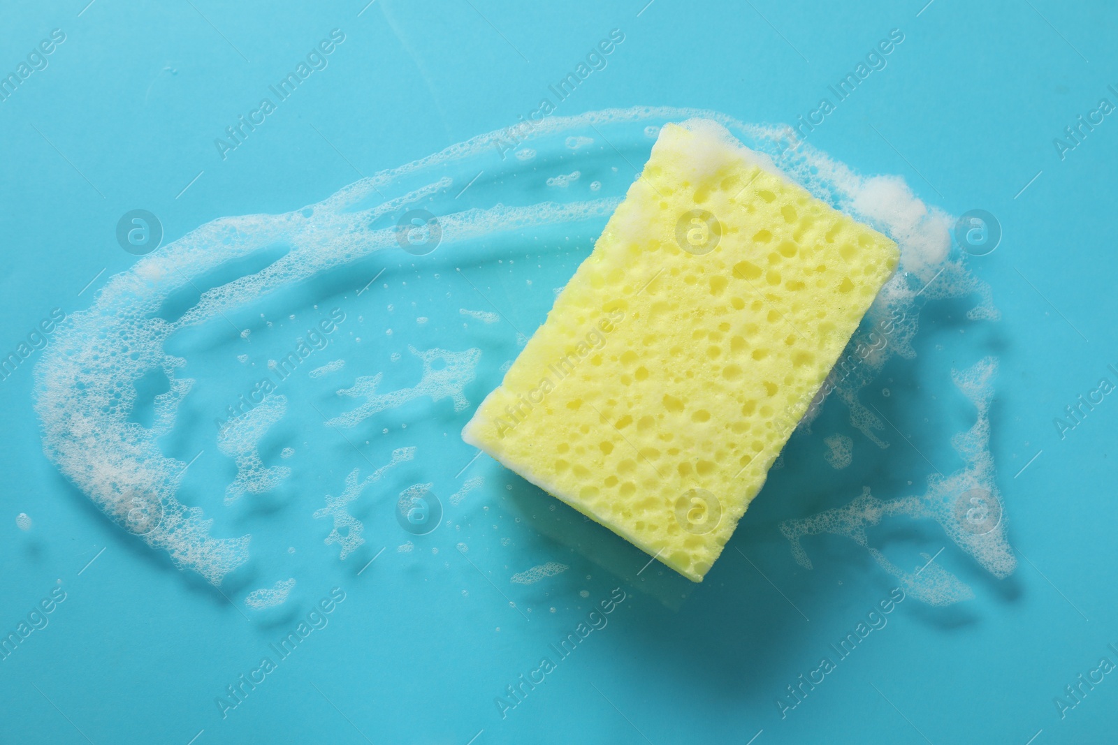 Photo of One cleaning sponge and foam on light blue background, top view. Space for text