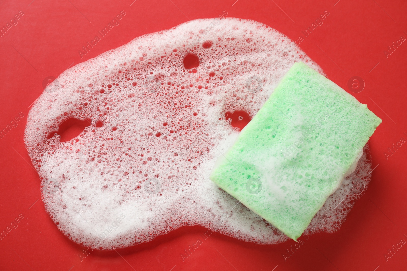 Photo of One cleaning sponge and foam on red background, top view. Space for text