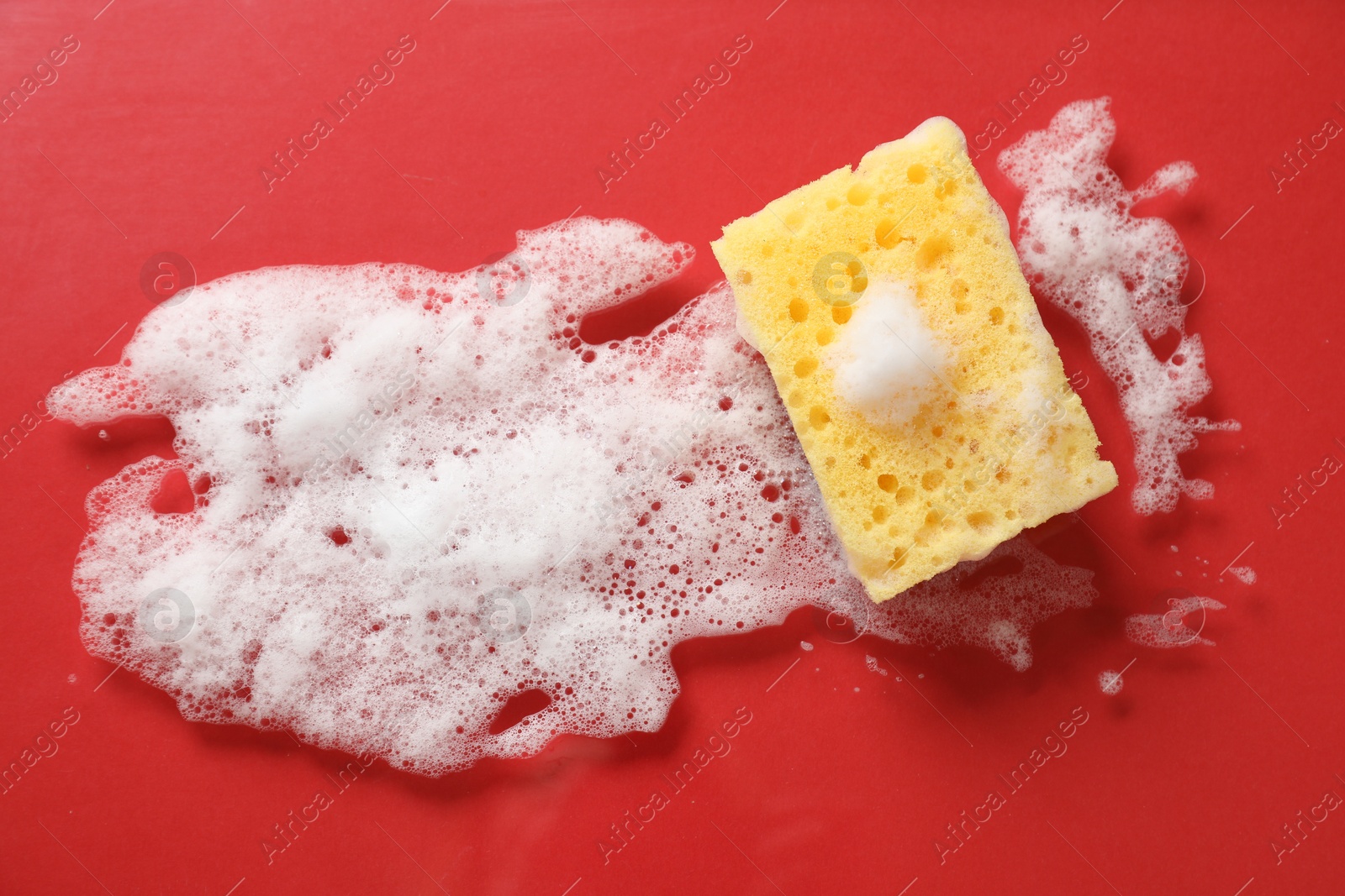 Photo of One cleaning sponge and foam on red background, top view. Space for text