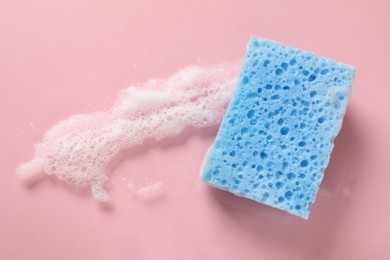 Photo of One cleaning sponge and foam on pink background, top view