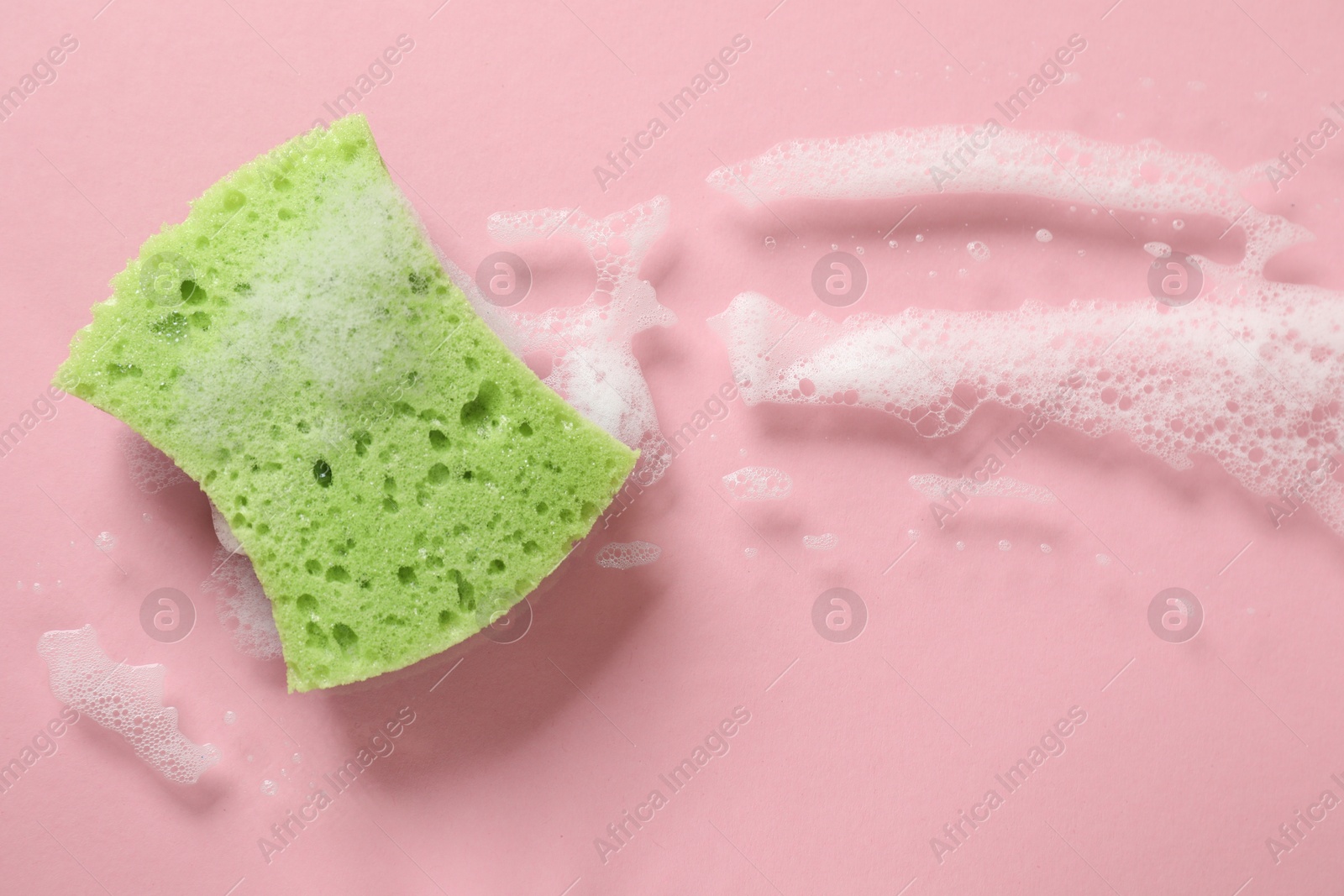 Photo of One cleaning sponge and foam on pink background, top view