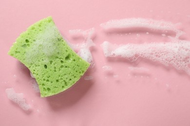 Photo of One cleaning sponge and foam on pink background, top view