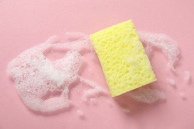 Photo of One cleaning sponge and foam on pink background, top view. Space for text