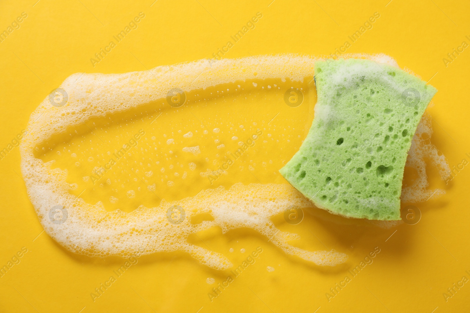 Photo of One cleaning sponge and foam on yellow background, top view. Space for text