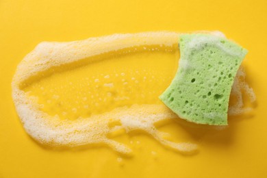 Photo of One cleaning sponge and foam on yellow background, top view. Space for text