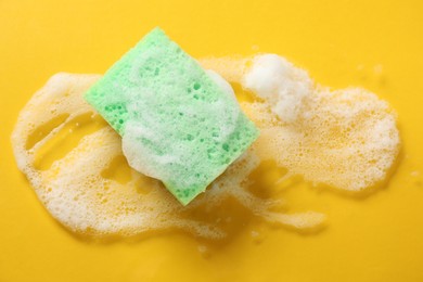 Photo of One cleaning sponge and foam on yellow background, top view