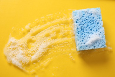 Photo of One cleaning sponge and foam on yellow background, top view. Space for text