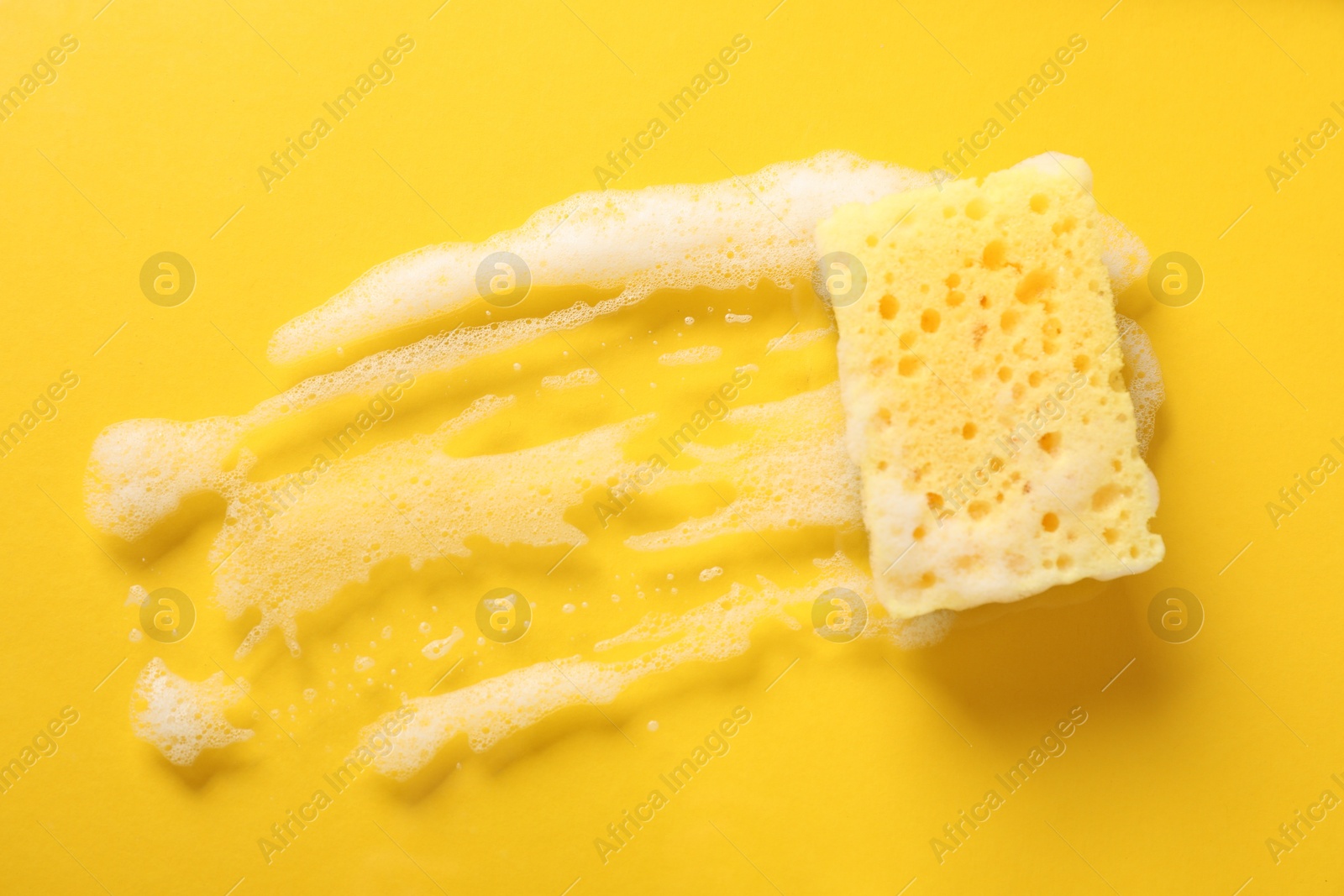 Photo of One cleaning sponge and foam on yellow background, top view. Space for text