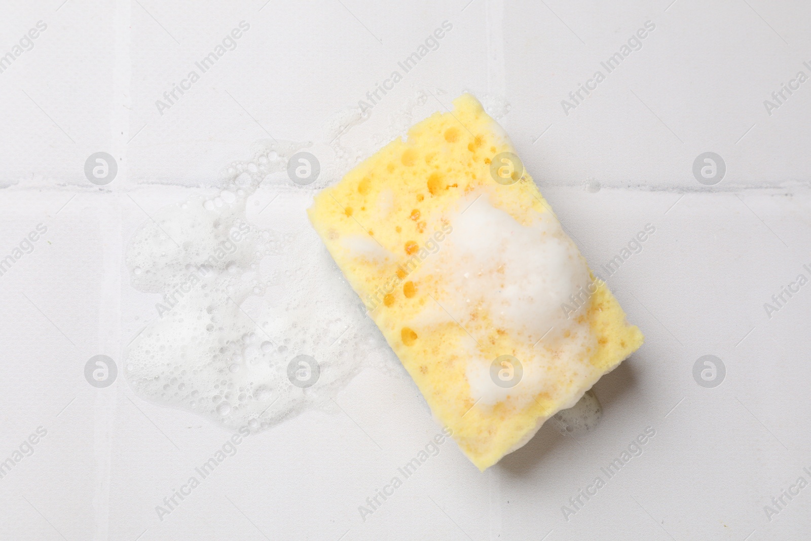 Photo of Sponge and foam on white tiled table, top view. Space for text