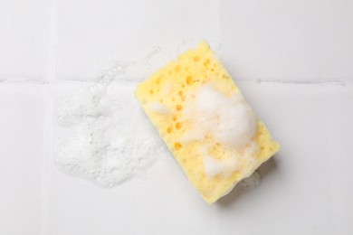 Photo of Sponge and foam on white tiled table, top view. Space for text