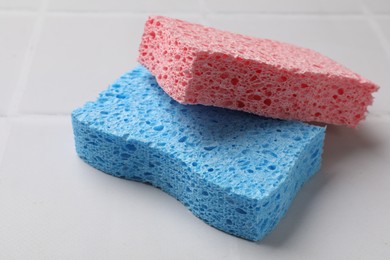 Photo of Soft sponges on white tiled table, closeup