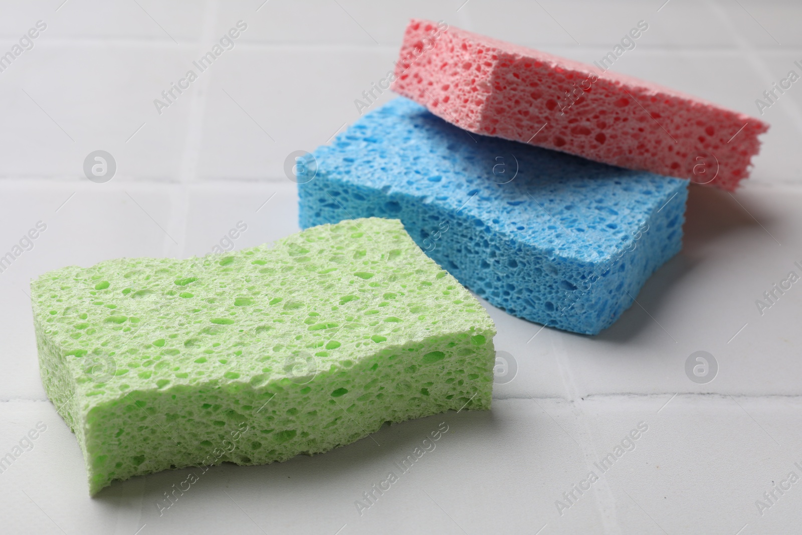 Photo of Soft sponges on white tiled table, closeup