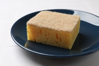 Photo of Sponge and plate on white tiled table, closeup