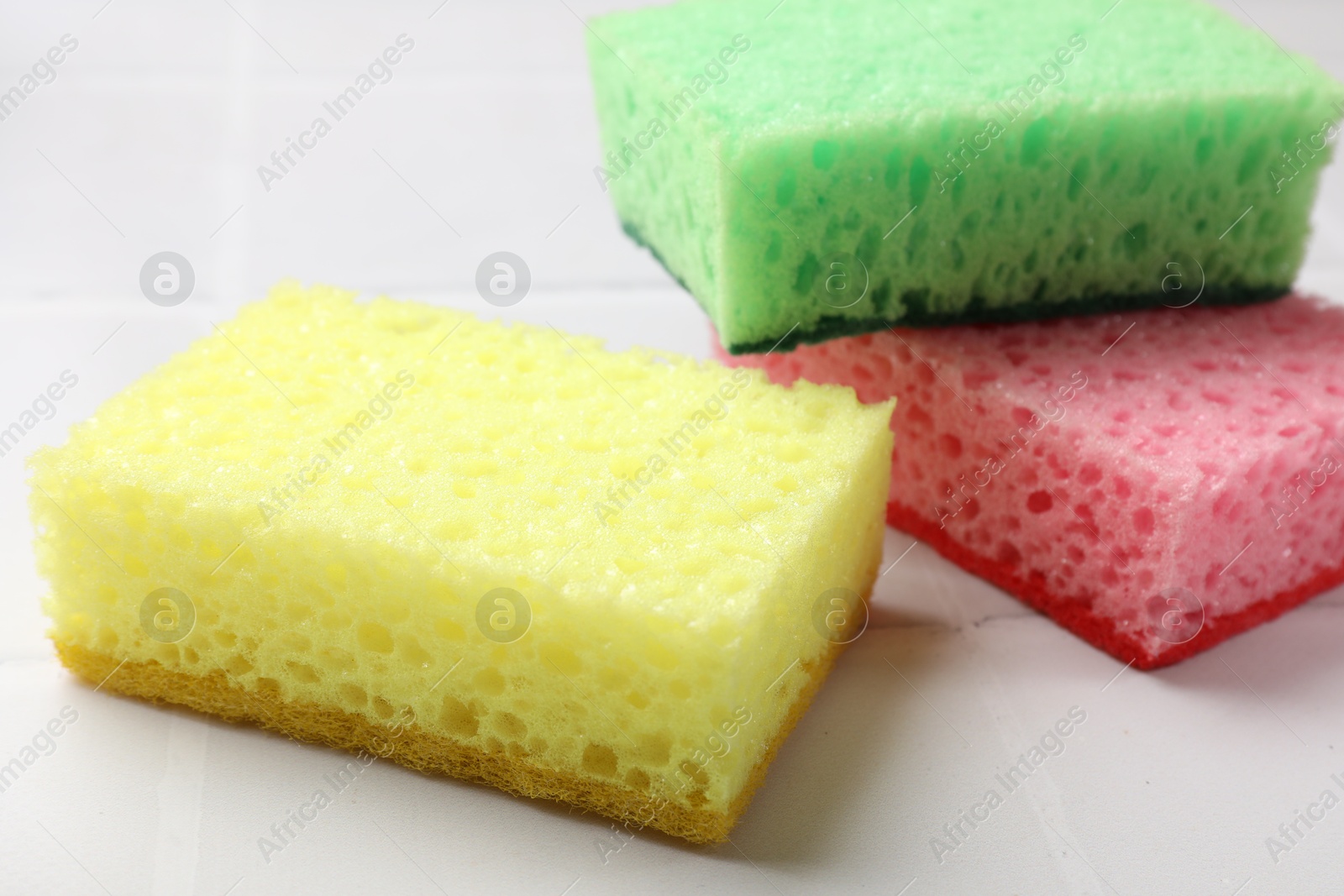 Photo of Soft sponges on white tiled table, closeup