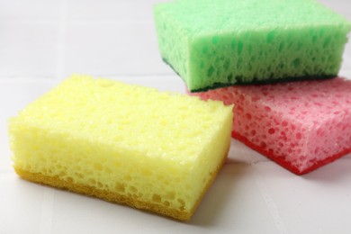 Photo of Soft sponges on white tiled table, closeup