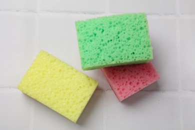 Photo of Soft sponges on white tiled table, flat lay