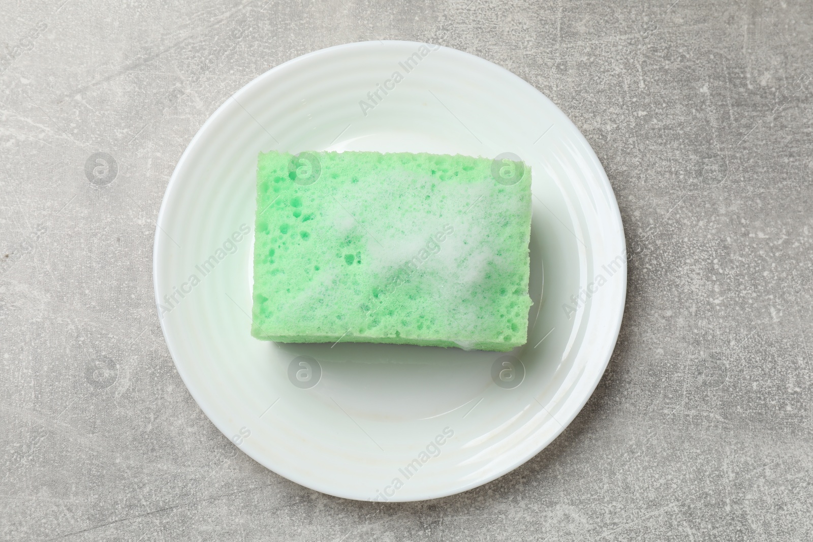 Photo of Sponge with foam and plate on light grey table, top view