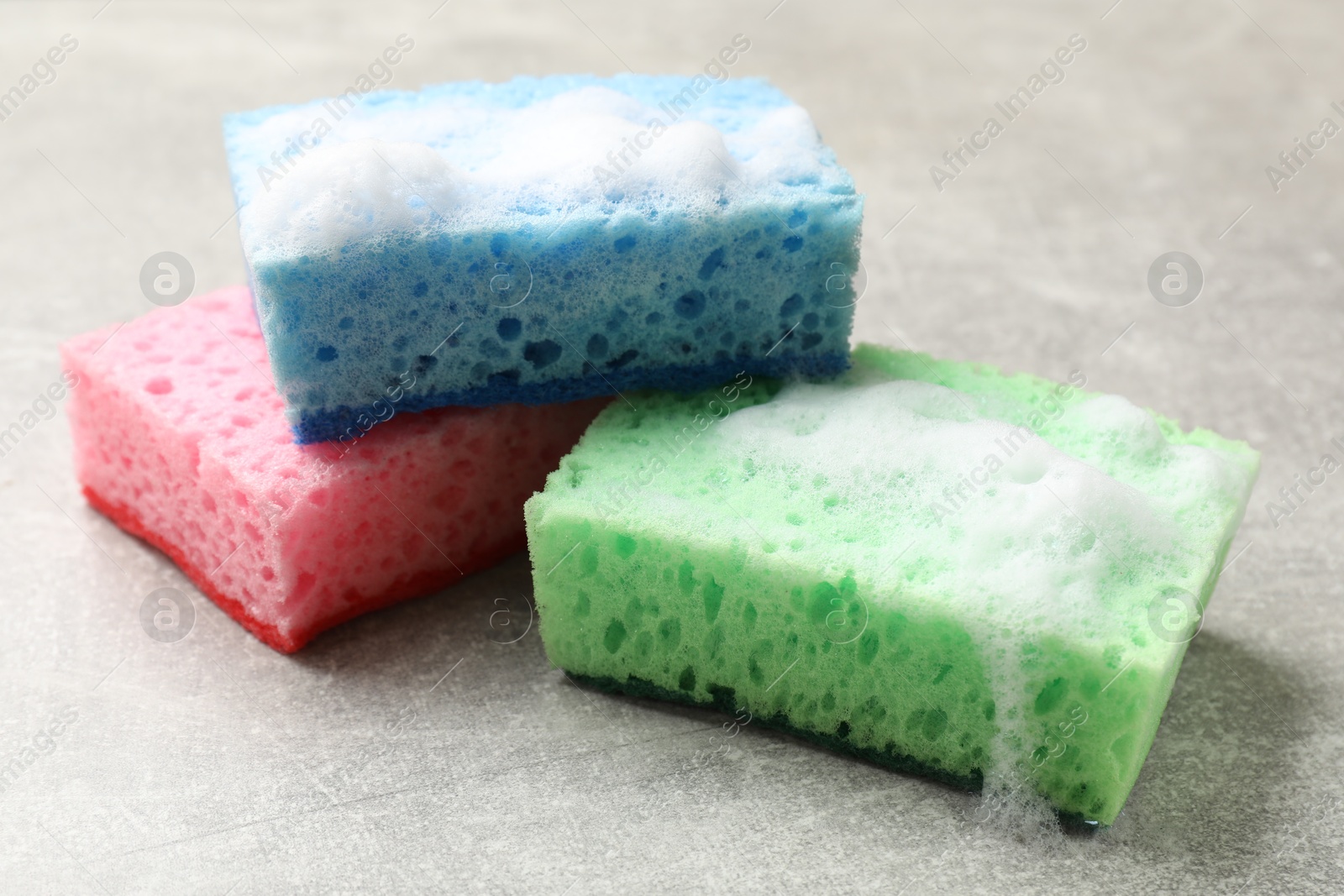 Photo of Sponges and foam on light grey table, closeup