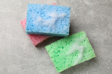 Photo of Sponges and foam on light grey table, flat lay