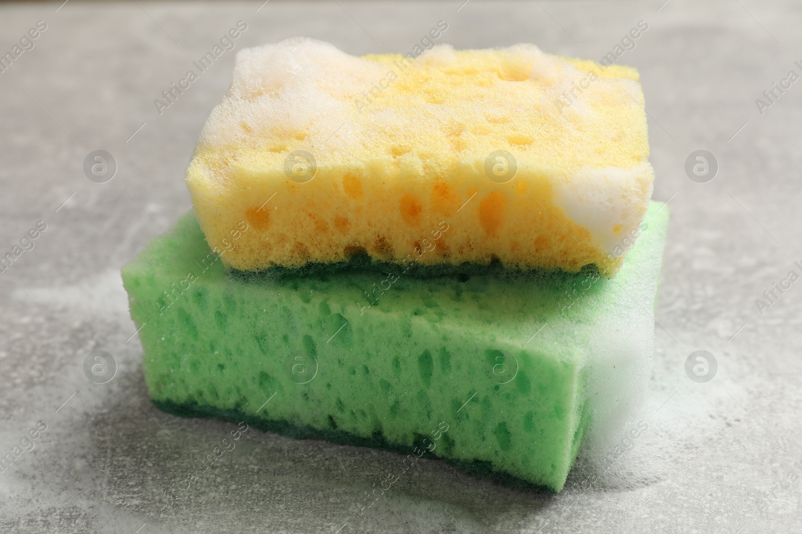 Photo of Sponges and foam on light grey table, closeup