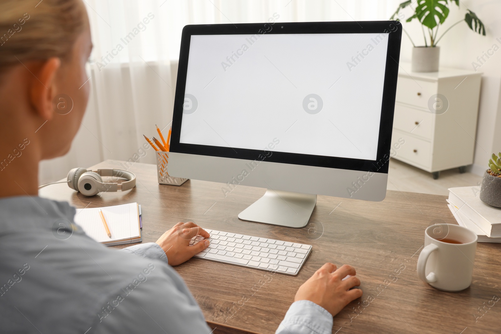 Photo of Woman working with computer monitor at wooden table in office, closeup. Mockup for design