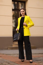 Beautiful businesswoman in stylish suit on city street