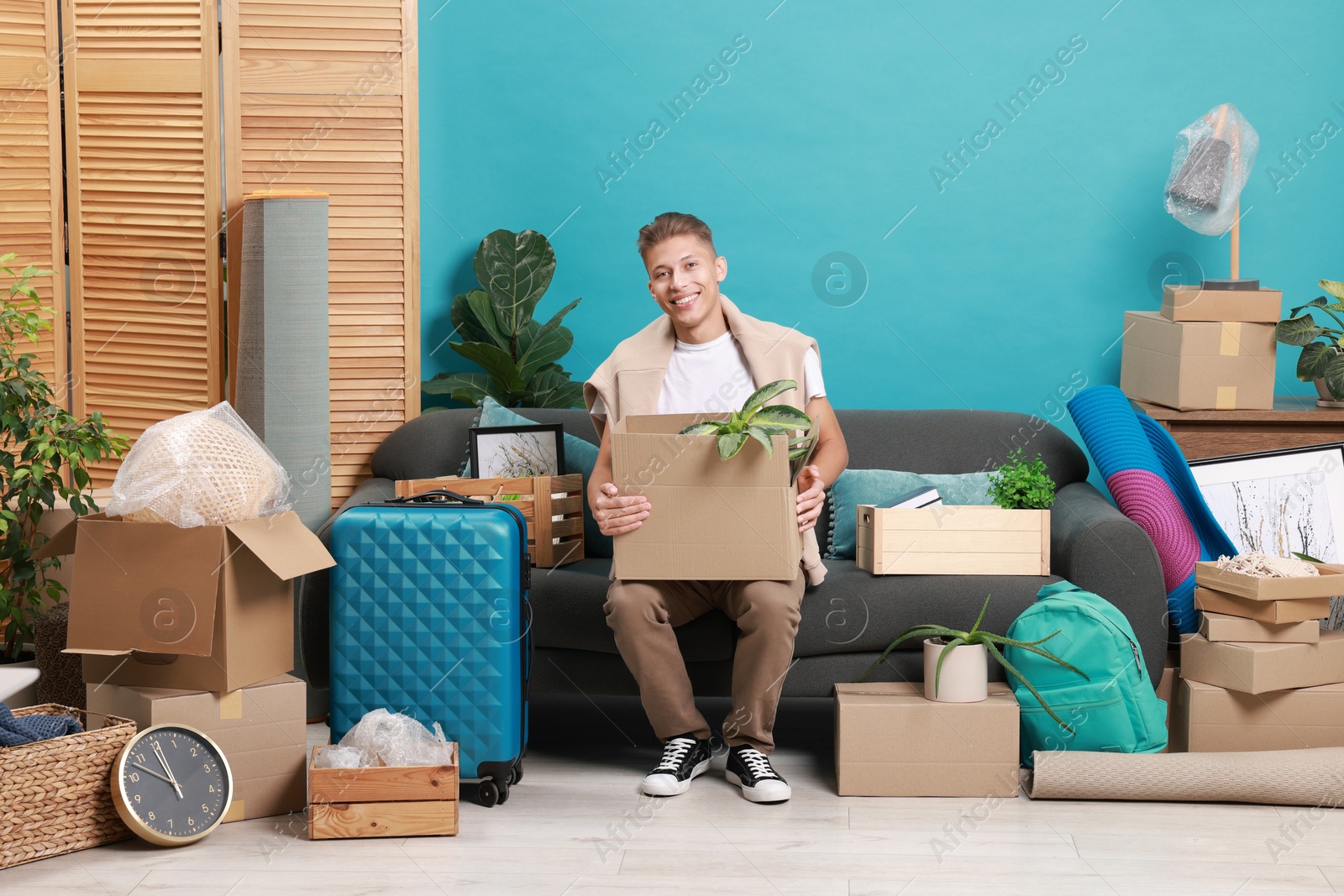 Photo of Happy man with different stuff in new apartment. Housewarming party