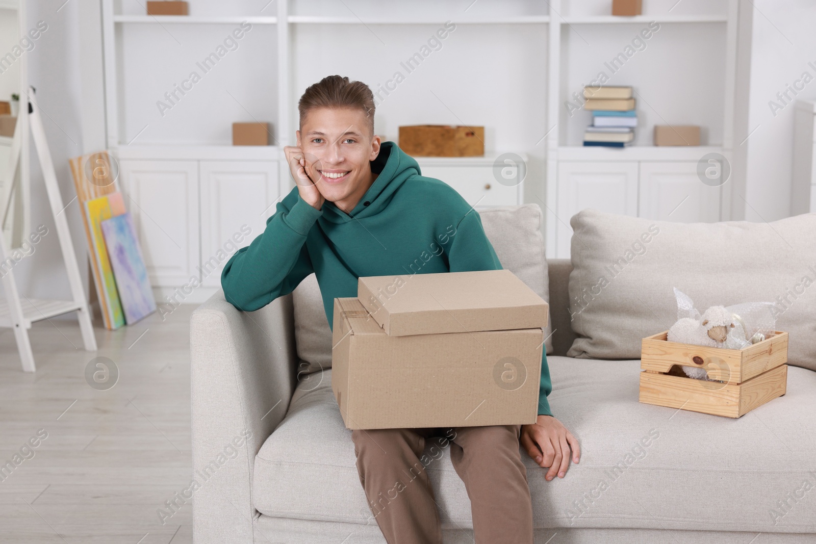 Photo of Happy man with moving boxes in new apartment. Housewarming party