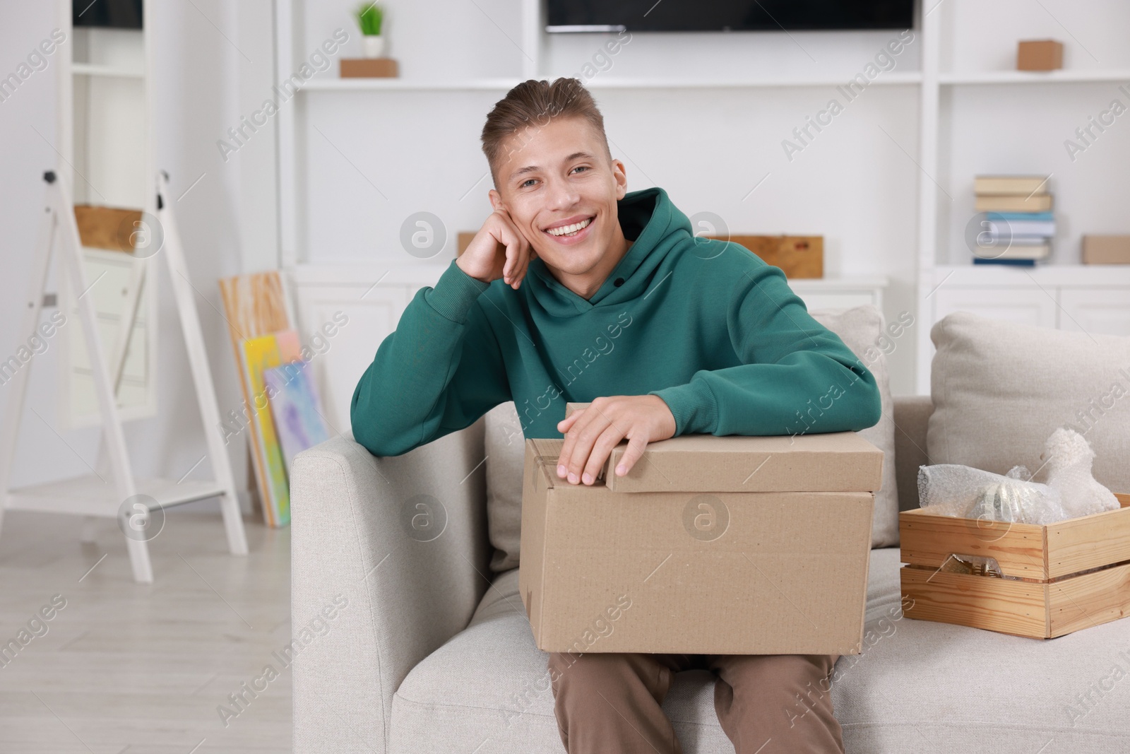 Photo of Happy man with moving boxes in new apartment. Housewarming party